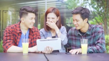 Lokantada ya da kafede otururken dijital tablet kullanan neşeli gençler