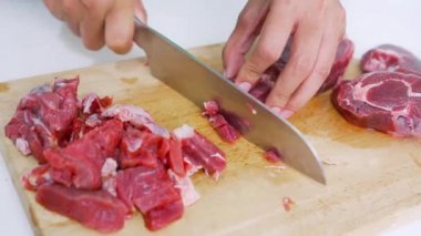 Yağlı bir kesme tahtasındaki bıçakla kırmızı eti keserken, mutfaktaki çeşniler...