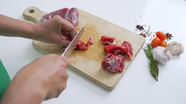 油っこいまな板の上にナイフで赤肉を切る手の閉鎖 キッチンに囲まれた条件ながら — ストック動画