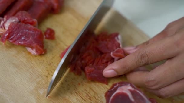 油っこいまな板の上にナイフで赤肉を切る手の閉鎖 キッチンに囲まれた条件ながら — ストック動画