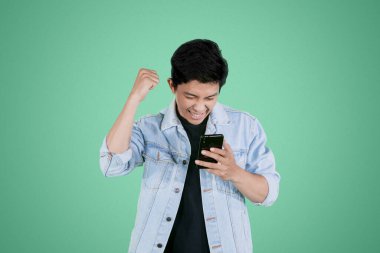 Stüdyoda cep telefonundan iyi haberler okurken başarısını ifade eden heyecanlı genç adam.