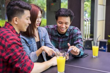 Boş zamanlarını kafede cep telefonlarına bakarak geçiren bir grup gencin portresi. 