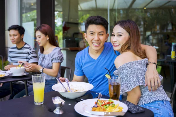 一对快乐的年轻夫妇在相机前微笑 桌上放着食物的画像 — 图库照片
