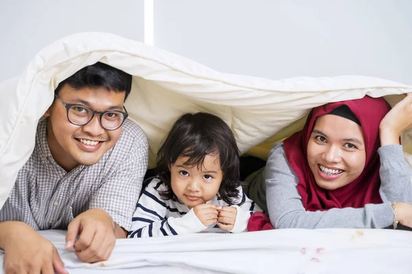 穆斯林父母和可爱的女儿在毛毯下玩耍 同时对着相机笑的画像 — 图库照片