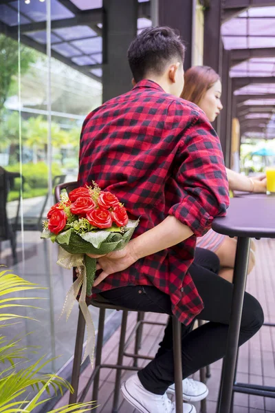 一个年轻男子坐在餐馆时背着一束鲜花的画像 — 图库照片