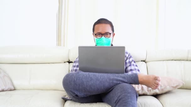 Mann Trägt Maske Und Arbeitet Mit Laptop Auf Couch — Stockvideo
