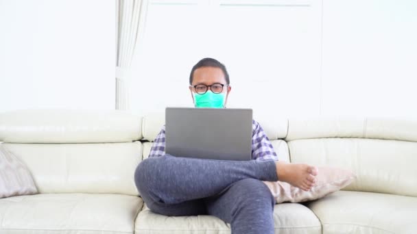 Uomo Indossando Maschera Lavorando Con Computer Portatile Sul Divano — Video Stock