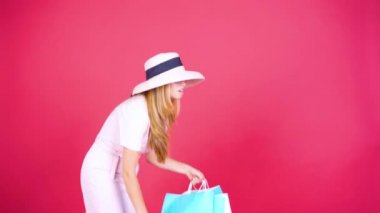 Stüdyoda alışveriş torbaları taşıyan yorgun genç bir kadın.