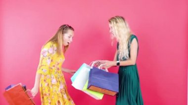  Stüdyoda iki genç kadın alışveriş torbaları taşıyor.