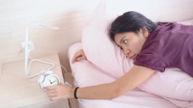 Genç bir kadın yatakta yatarken sıkılıyor. 