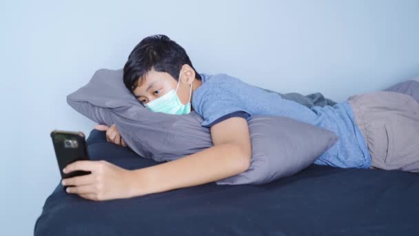 Preteen boy using a smartphone on bed - Depositphotos 