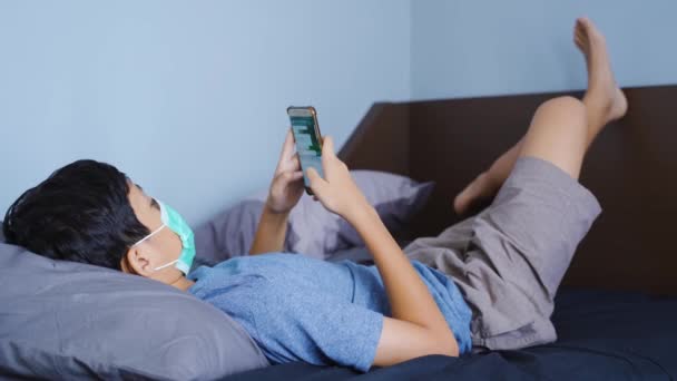 ベッドの上でスマートフォンを使用して十代の男の子 — ストック動画