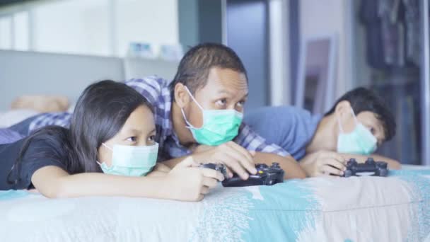 Retrato Pai Seus Filhos Jogando Videogame Cama Enquanto Vestindo Máscara — Vídeo de Stock