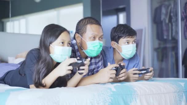 Retrato Pai Seus Filhos Jogando Videogame Cama Enquanto Vestindo Máscara — Vídeo de Stock