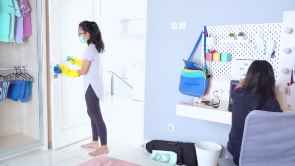フェイスマスクをしながら消毒剤を使用して家を掃除するアジアの女性の側面図 — ストック動画