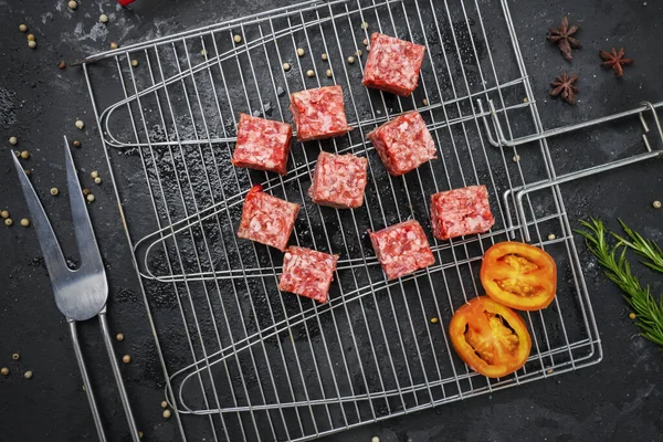 Flat lay of raw beef cube steak on the grill with tomato