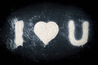 Kuma yazılmış, siyah arkaplanda kalp sembolü olan seni seviyorum metni.