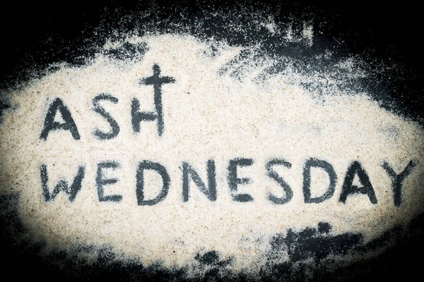 Flat lay of Ash Wednesday text written on the sand with black background