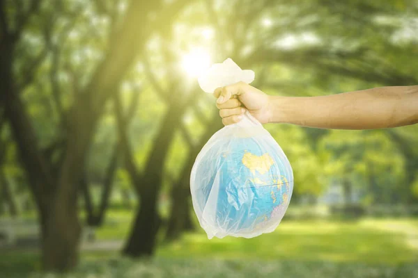 Рука Держит Глобус Пластиковом Пакете Зелеными Деревьями Заднем Плане Парке — стоковое фото