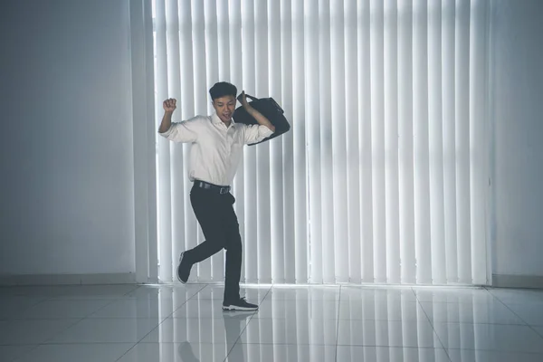 全身而退的年轻商人拿着公文包在办公室里跳舞 — 图库照片