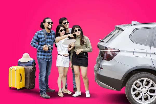 Portret Grupy Młodych Turystów Patrzących Coś Stojąc Samochodem Różowym Tle — Zdjęcie stockowe