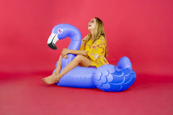 Portret Szczęśliwej Kobiety Siedzącej Platformie Flamingowej Śmiejącej Się Studio Czerwonym — Zdjęcie stockowe