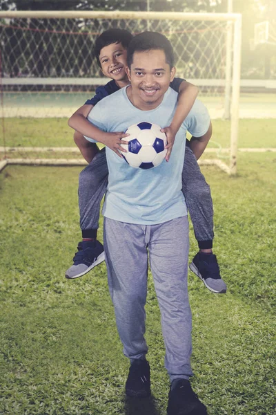 小男孩和他的父亲站在足球场时拿着球的画像 — 图库照片