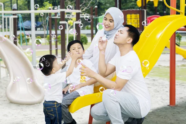 遊び場で余暇を楽しみながら泡石鹸を再生陽気なイスラム教徒の家族の肖像画 — ストック写真