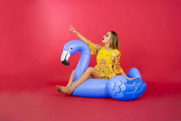 Retrato Mulher Loira Apontando Algo Enquanto Está Sentado Flamingo Flutuar — Fotografia de Stock