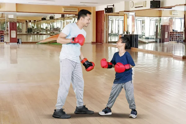 フィットネスセンターに立っている間にボクシングの練習をしている若い男と小さな息子の肖像 — ストック写真