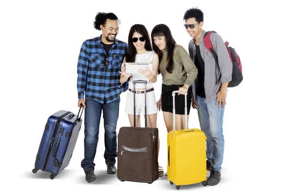 白い背景に隔離されたスーツケースを持ちながら 一緒にデジタルタブレットを見ている若い観光客の完全な長さ — ストック写真
