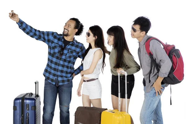 白い背景に孤立したスーツケースを持ちながら携帯電話で自撮り写真を撮る若い観光客の肖像 — ストック写真