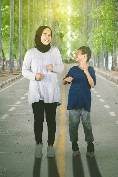 全长的年轻女子和她的儿子穿着运动服在公园里慢跑 — 图库照片