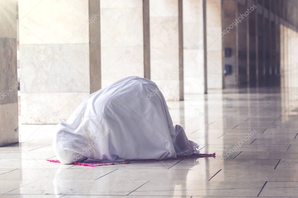 Portrait of muslim woman posing prostration in the mosque while doing worship to Allah 