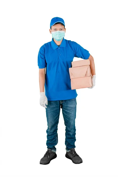 男人穿着蓝色的递送制服和面罩 腰包着一堆包裹 被白色的背景隔开 — 图库照片