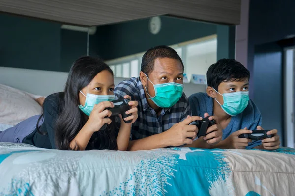 Portrait of children and father playing video game while wearing medical mask and stay at home