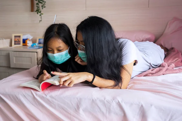 Retrato Madre Hija Jóvenes Leyendo Libro Cama Mientras Usan Máscara —  Fotos de Stock