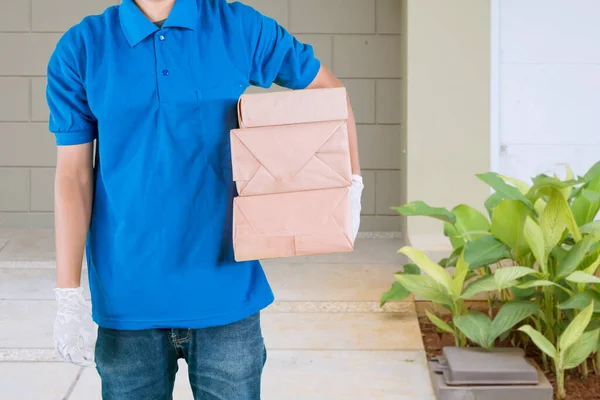在自家院子里 身穿蓝色送货制服的身份不明男子拿着一堆堆包包裹在自己臀部周围的衣服 — 图库照片