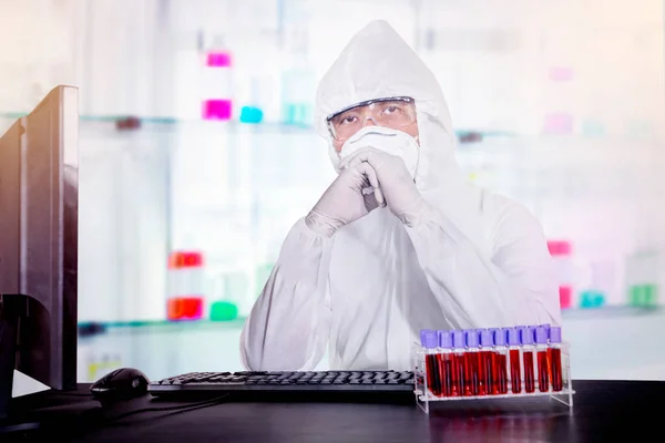 在实验室的办公桌前摆姿势时穿着危险垫套装的身份不明的科学家的画像 — 图库照片
