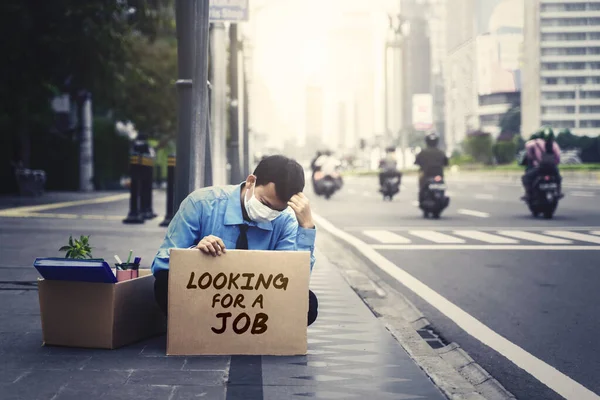 ジャカルタ インドネシア 2020年 2020年 5月12日 道端に座りながら仕事を探すという文字の入った段ボール箱を持ったストレス男性労働者 Covid 19インパクトコンセプト — ストック写真