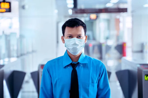 JAKARTA - Indonesia. May 12, 2020: Young businessman wearing a mask and looking at the camera while standing on the empty MRT station during quarantine