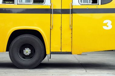 Okul otobüsü yan görünüm, kanat bir tekerlek, sarı otobüs ile.