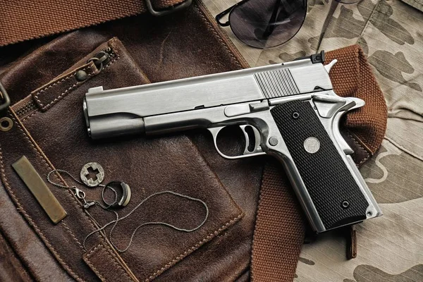Самозарядний пістолет, що лежить над шкіряною сумкою, пістолет .45 . — стокове фото