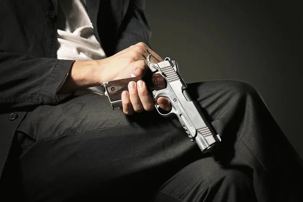 Muž sedí na židli drží zbraň. — Stock fotografie