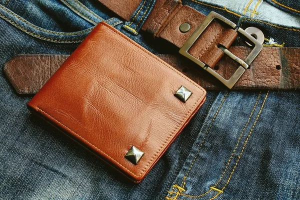 Men's accessories. Brown leather wallet on jeans background.
