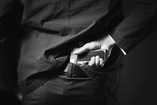 Un hombre, un policía o un gángster ocultando su arma a sus espaldas — Foto de Stock