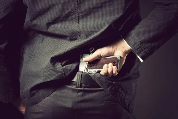 Arma escondida. Um homem, policial ou gangster escondendo sua arma nas costas — Fotografia de Stock