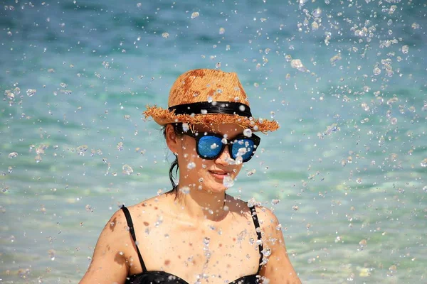 Sommartid, lekfulla flicka stänk på stranden, kvinna med solglasögon i bikini. — Stockfoto