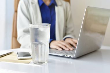 Ofiste bir bardak içme su ofis masasında çalışırken iş kadın içki taze iyi sağlık kavramı için içme suyu.
