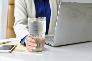 Ofiste bir bardak içme su ofis masasında çalışırken iş kadın içki taze iyi sağlık kavramı için içme suyu.